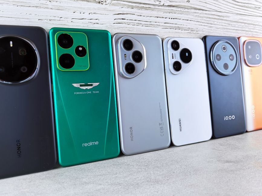A collection of various smartphones lined up on a textured surface, showcasing different designs.